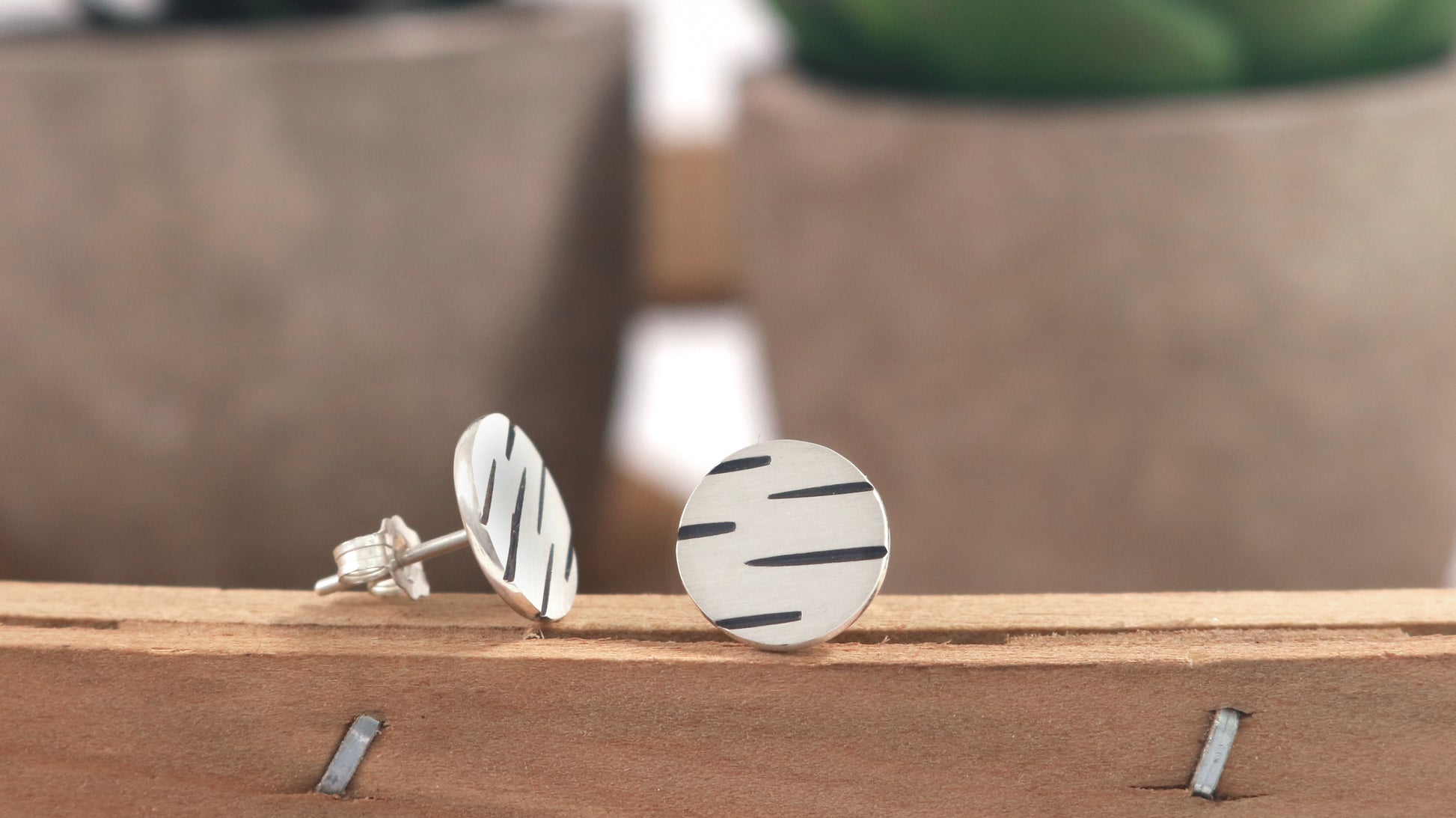 Round silver disc studs with offset black lines randomly spaced.