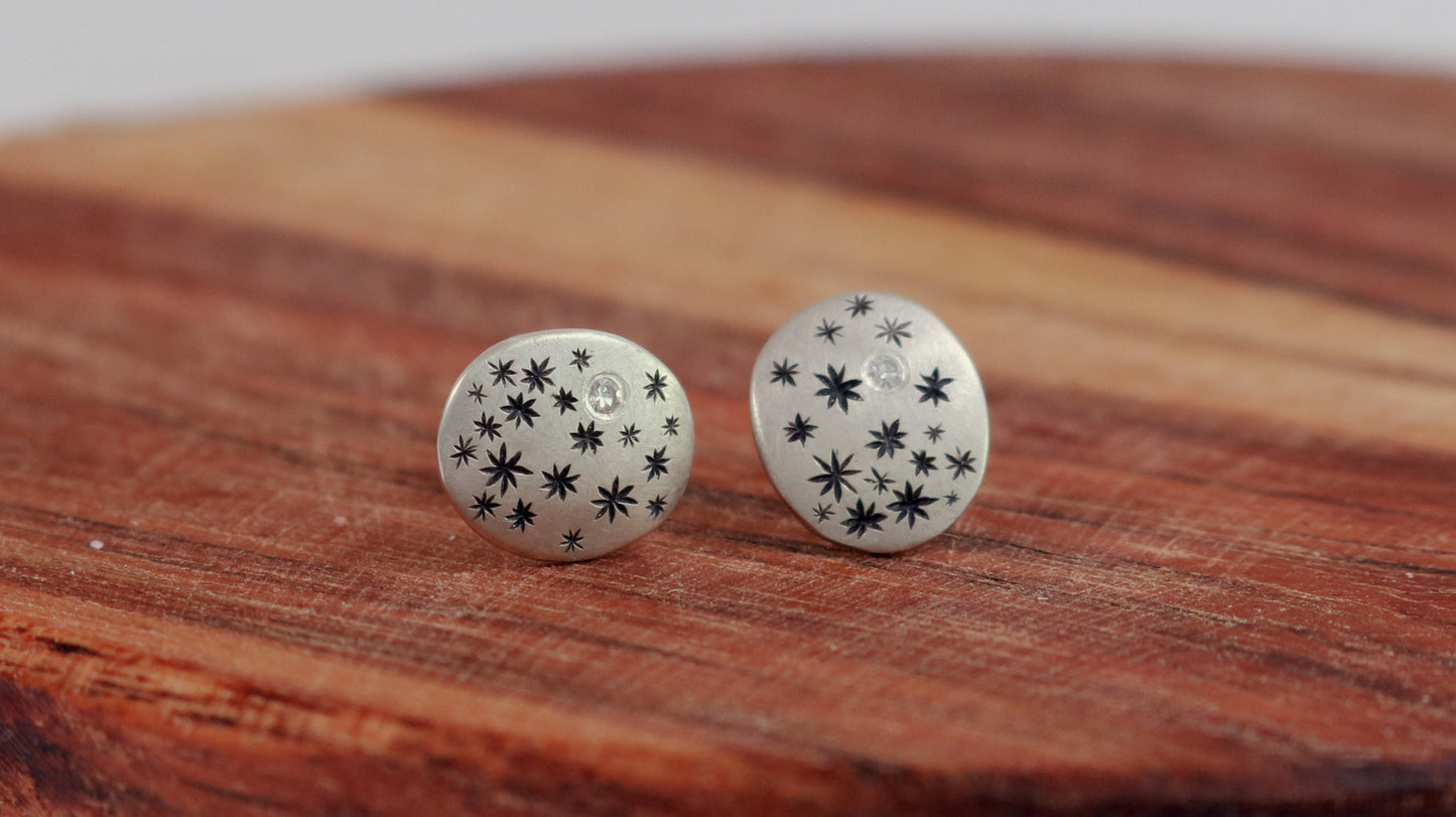 A pair of domed oval sterling silver studs covered in hand carved, black stars and one white diamond..