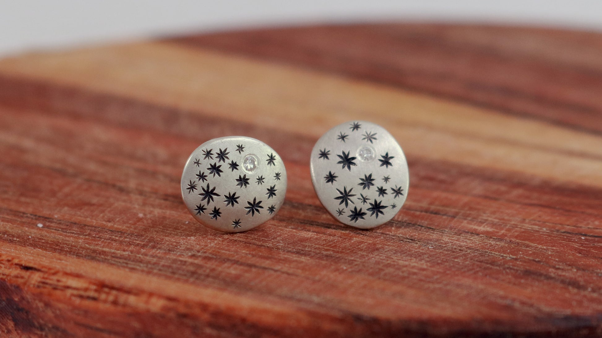 A pair of domed oval sterling silver studs covered in hand carved, black stars and one white diamond..