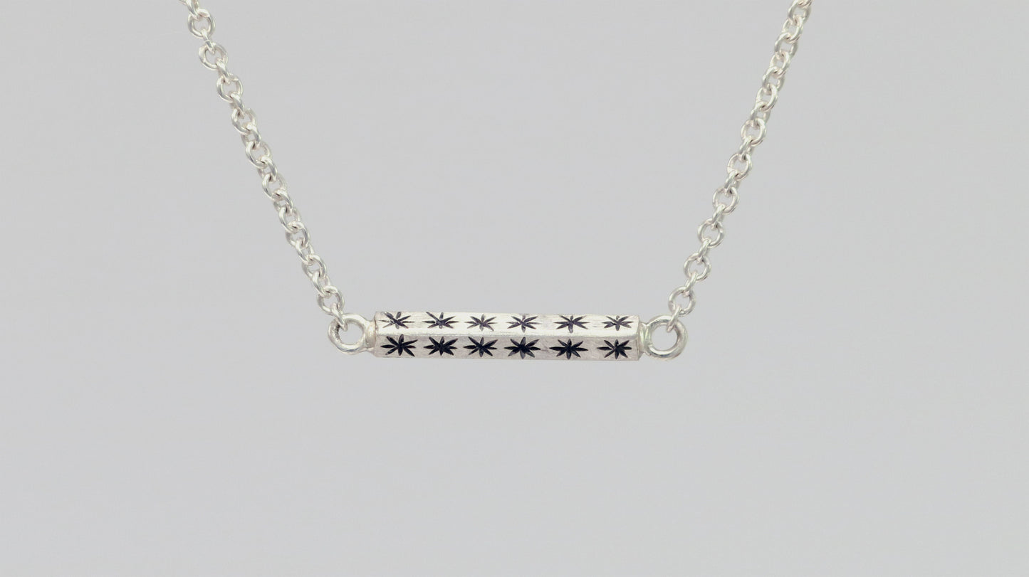 Sterling silver bar necklace with hand cut black stars on every side on a sterling silver chain.