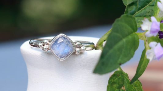 Natural cushion cut rainbow moonstone set in sterling silver with 2 silver bubble pyramid accents on a sterling silver ring band.