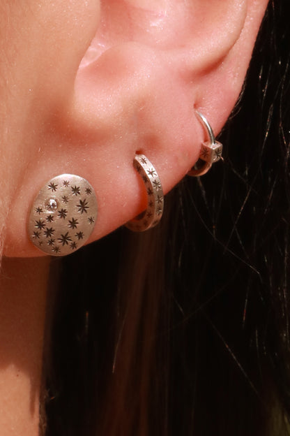 A pair of domed oval sterling silver studs covered in hand carved, black stars and one white diamond.. 