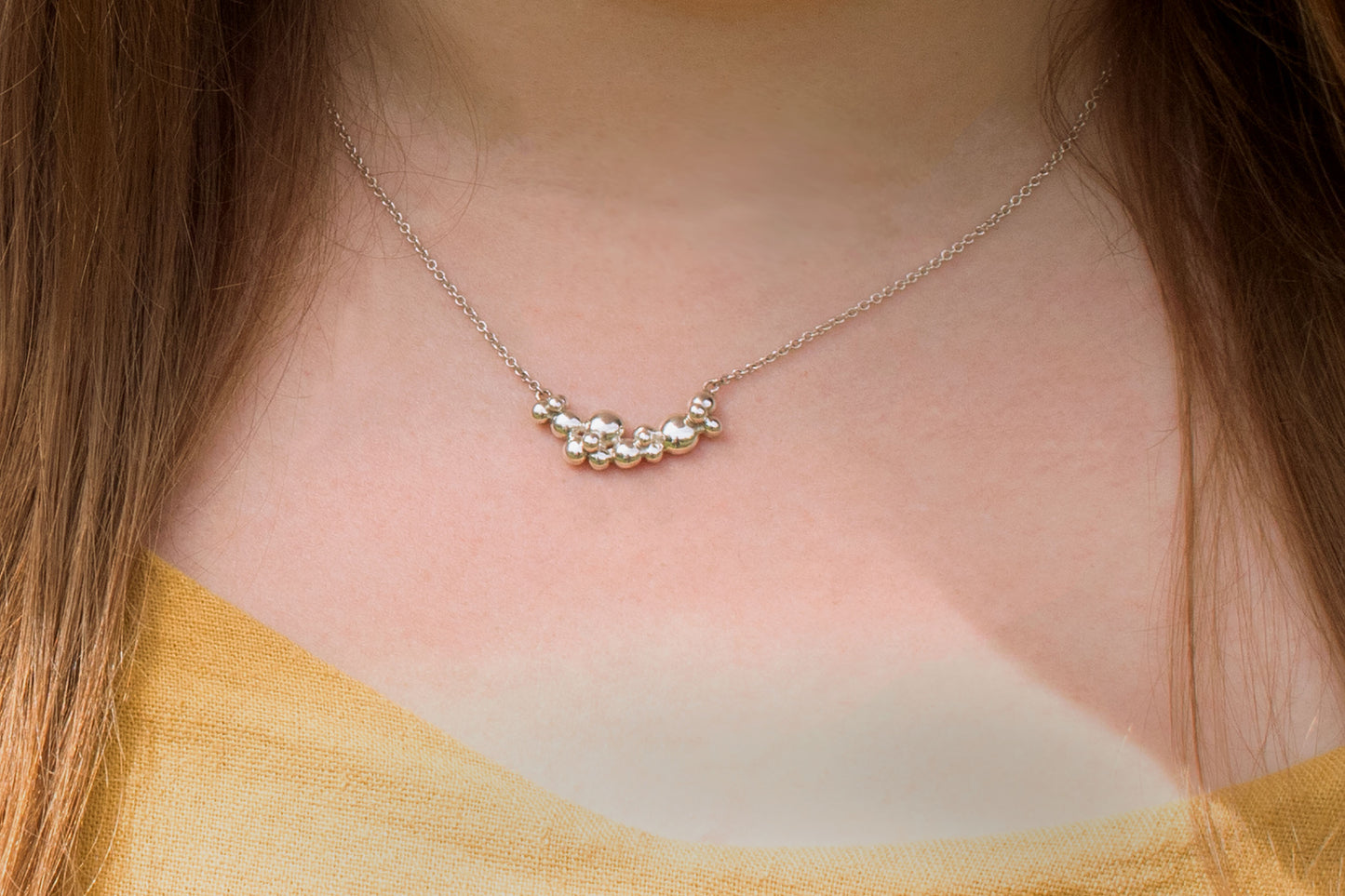 A curved cluster of silver bubbles of different sizes on a sterling silver chain.