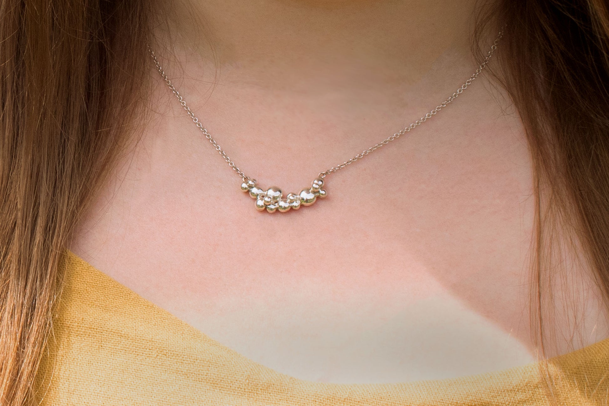 A curved cluster of silver bubbles of different sizes on a sterling silver chain.