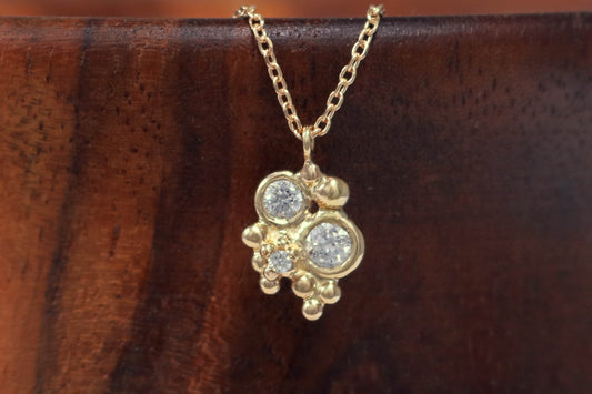 Three diamonds, decreasing in size, set in 14k yellow gold bezels, surrounded by randomly placed gold bubbles. on a 14k yellow gold chain.