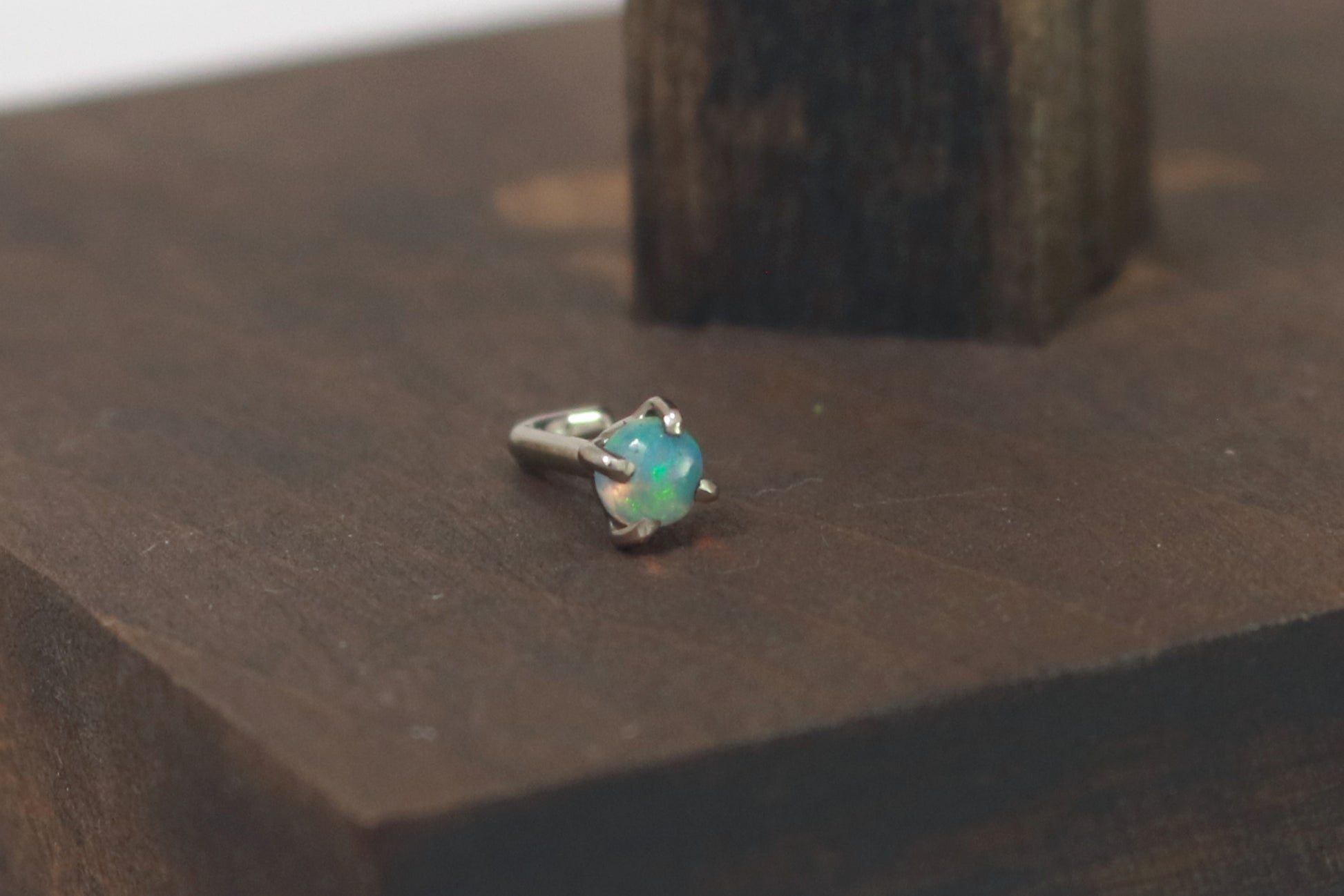 A white gold nose stud with a round opal set with prongs.