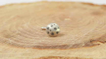 A 5mm domed, silver, nose stud with hand carved black stars.