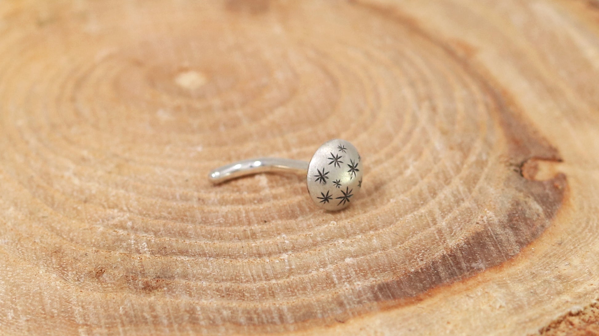 A 5mm domed, silver, nose stud with hand carved black stars.