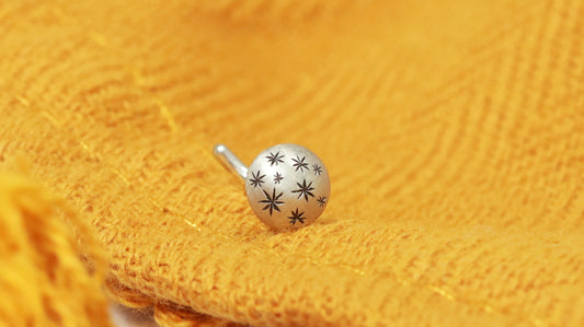 A 5mm domed, silver, nose stud with hand carved black stars.