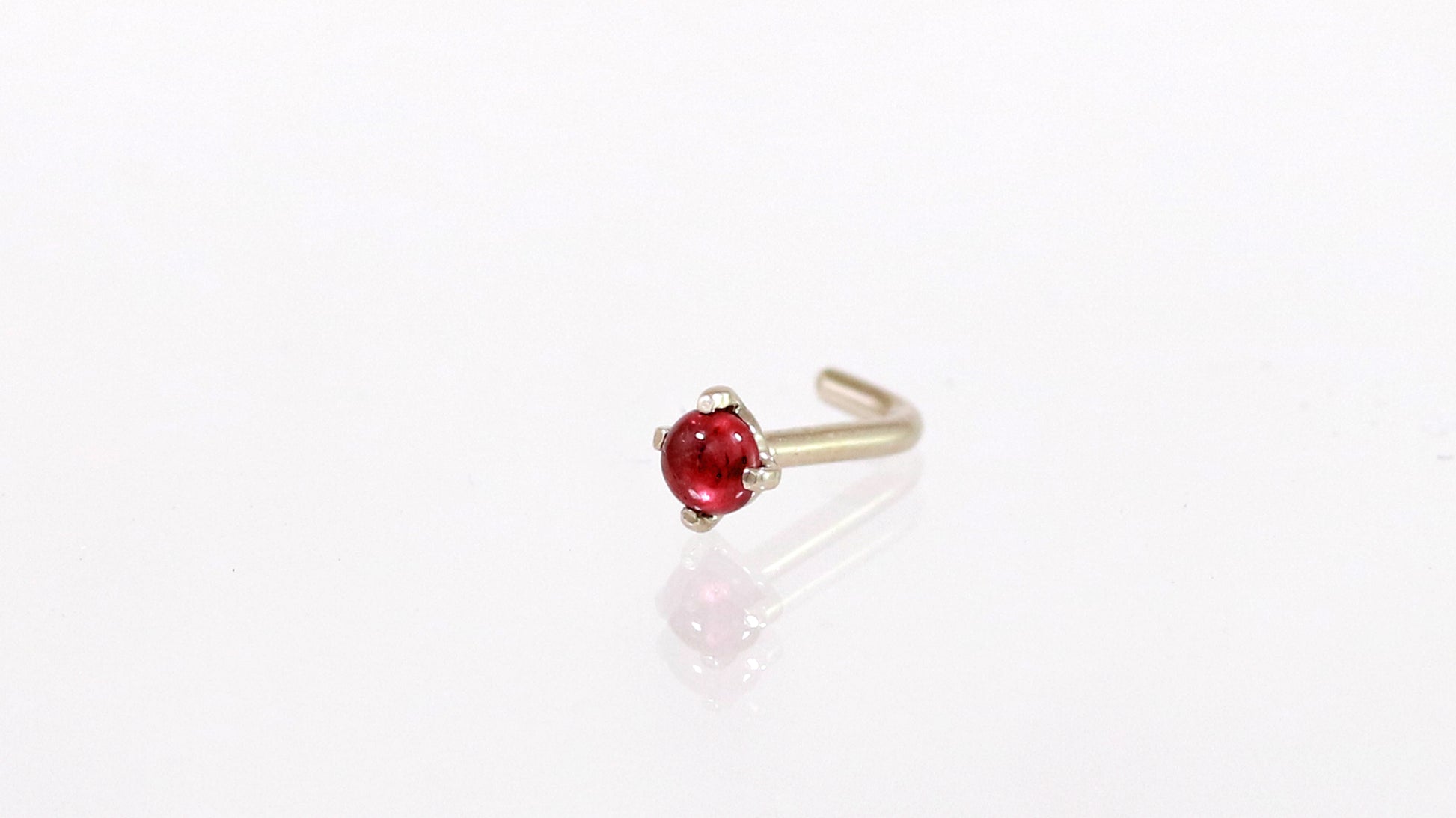 A 14k white gold nose stud with a round ruby set with prongs.