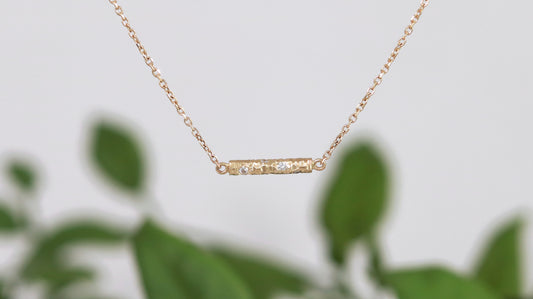 Solid 14k gold bar necklace, textured and set with 6 diamonds.