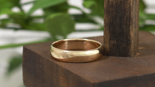 A slightly domed, polished, solid 14k yellow gold ring band, 5mm thick.