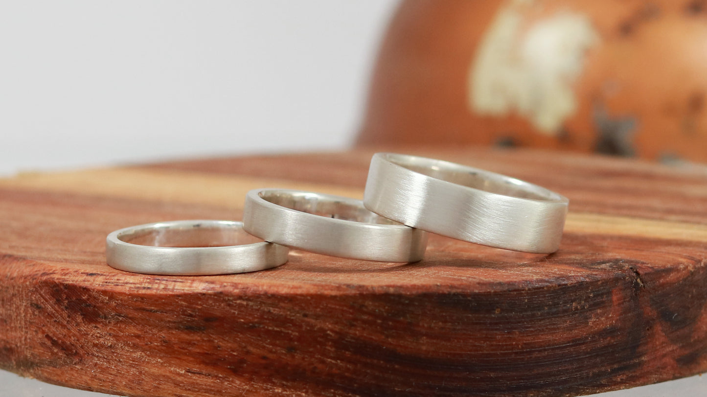 A group of various thickness sterling silver ring bands with a matte finish outside & polished finish inside.