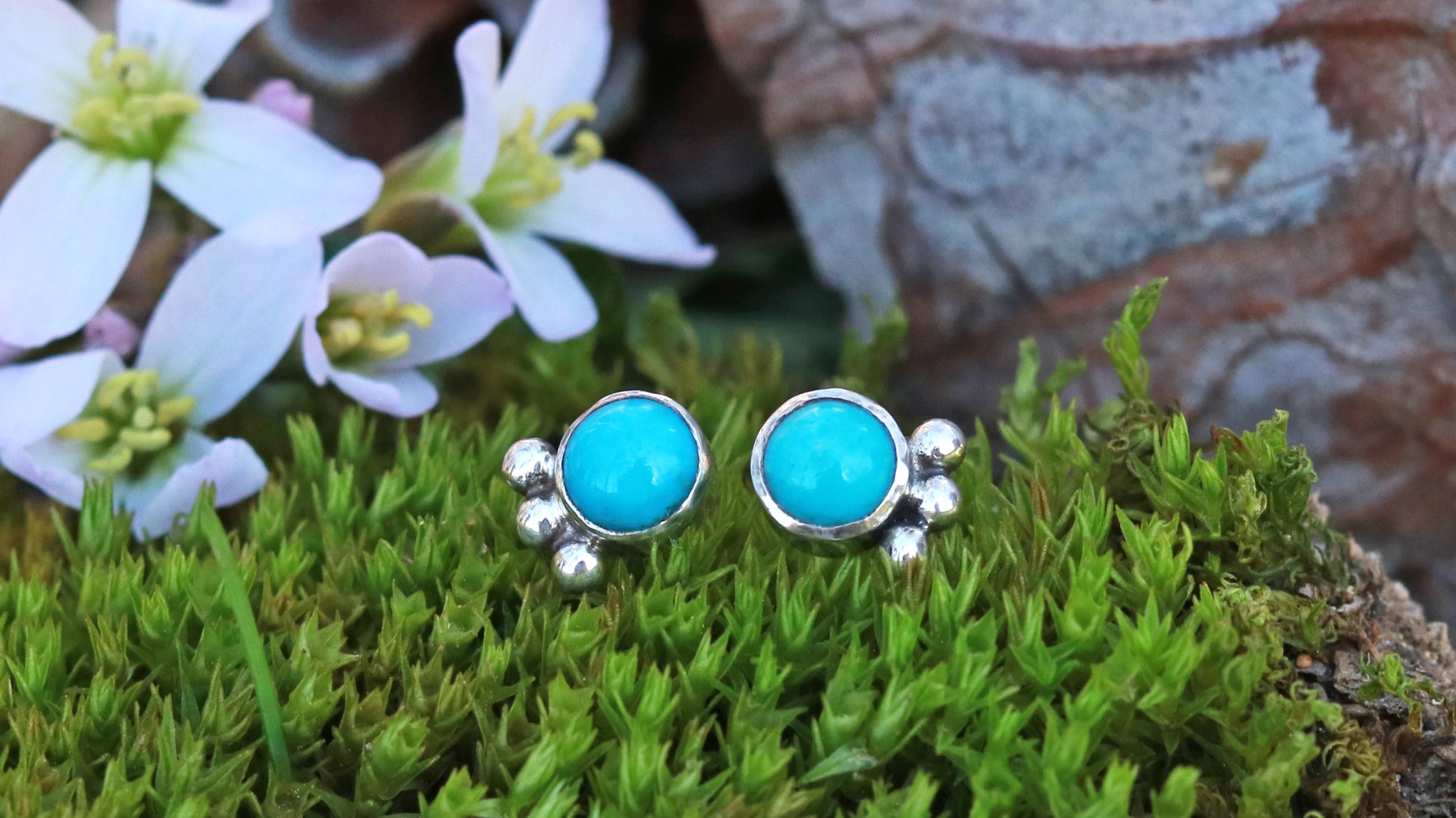 A pair of 5mm, round turquoise stones set in sterling silver with three silver bubbles aligned along the bezel.