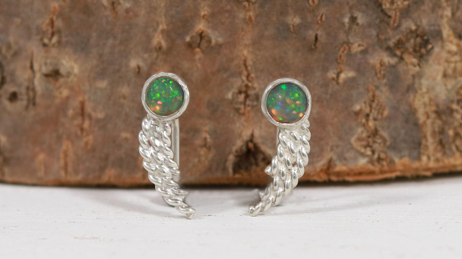 Stud earrings, round natural gemstones set in sterling silver bezels with silver, curved twisted tails meant to be worn two ways. 