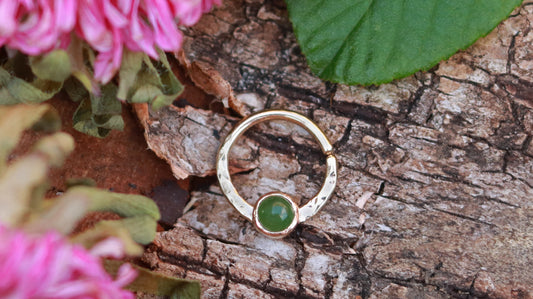 A 14k yellow gold hoop, flattened and textured at the bottom, with a round jade set in a bezel on top of the textured flat section.
