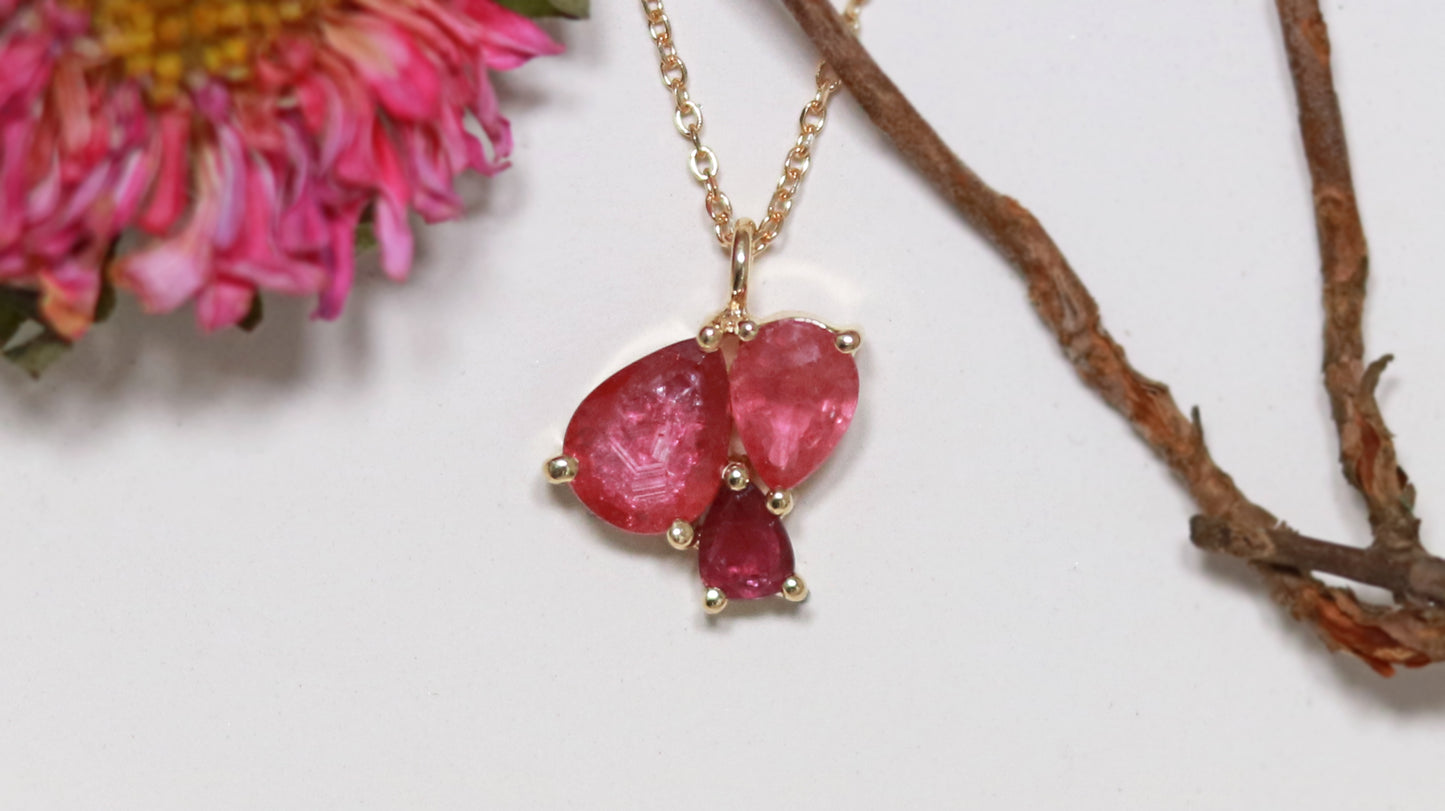 3 natural pear rubies in different shades of red set in solid 14k yellow gold on a gold chain.