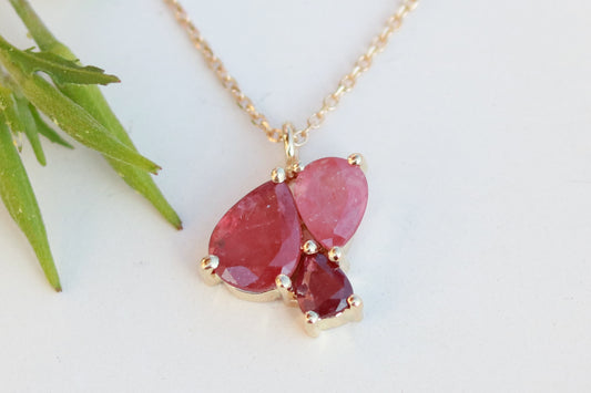 3 natural pear rubies in different shades of red set in solid 14k yellow gold on a gold chain.