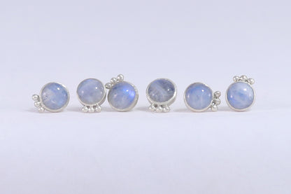 Three pairs of round rainbow moonstone stud earrings with 3 silver bubbles in a row at the bottom. 