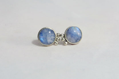 A pair of round rainbow moonstone stud earrings with 3 silver bubbles in a row on the sides. 