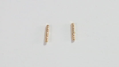 14k yellow gold bar studs with a rough hammer texture.