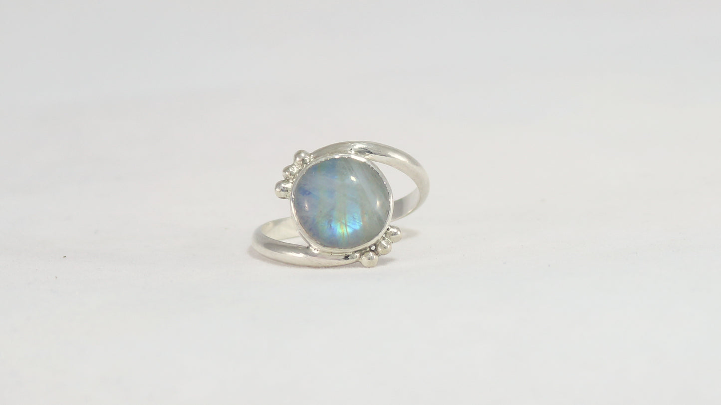 Round natural rainbow moonstone set in sterling silver bezel on a bypass ring band with silver bubble accents. 