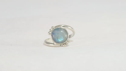 Round natural rainbow moonstone set in sterling silver bezel on a bypass ring band with silver bubble accents. 