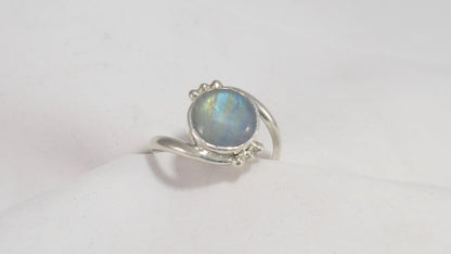 Round natural rainbow moonstone set in sterling silver bezel on a bypass ring band with silver bubble accents. 