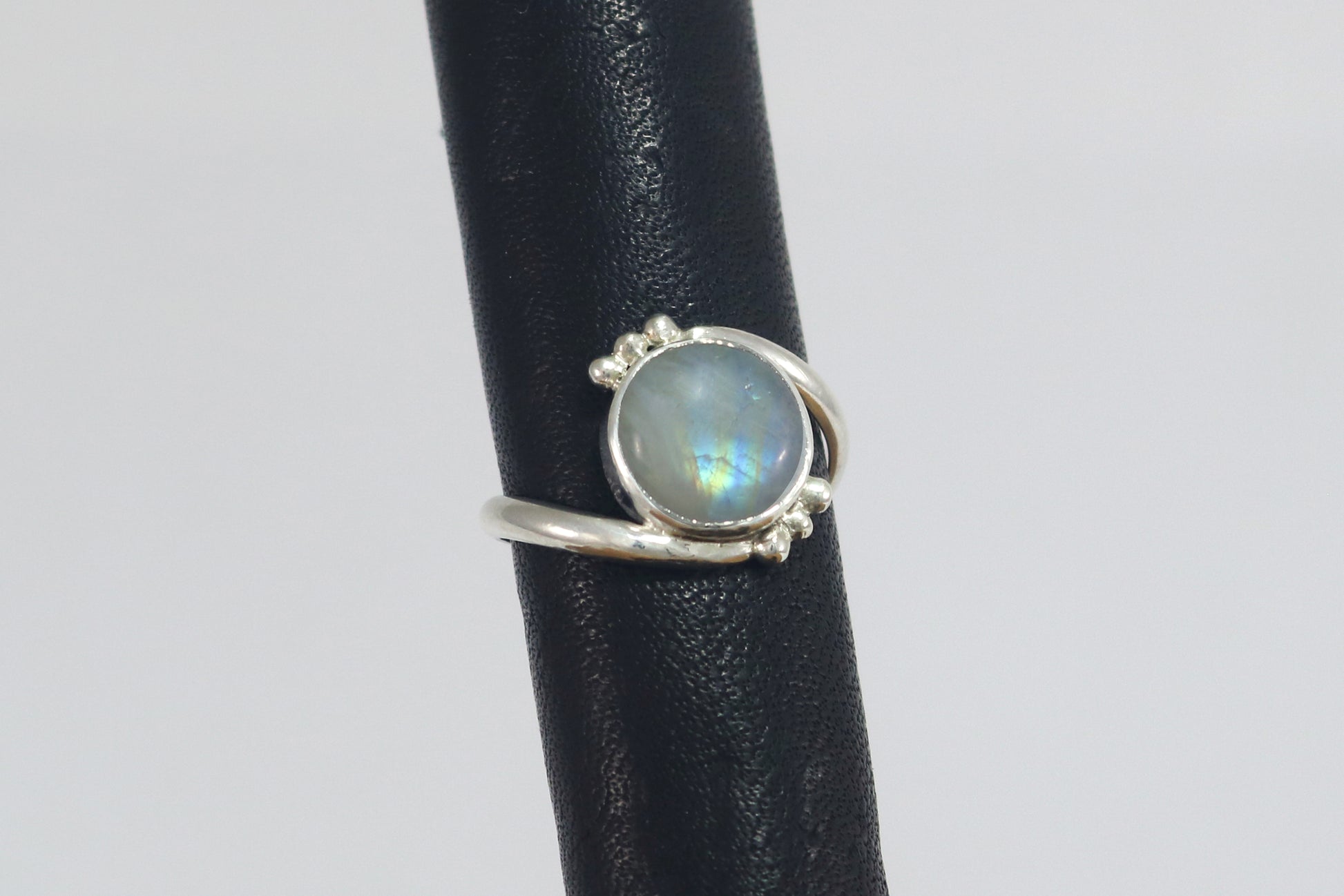 Round natural rainbow moonstone set in sterling silver bezel on a bypass ring band with silver bubble accents. 