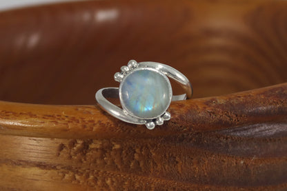 Round natural rainbow moonstone set in sterling silver bezel on a bypass ring band with silver bubble accents. 