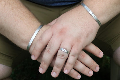 A model wearing a 6mm thick silver ring band with randomly spaced black line details.