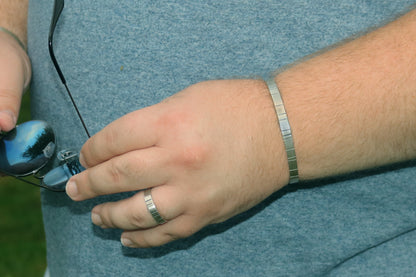 A model wearing a 6mm thick silver ring band with randomly spaced black line details.