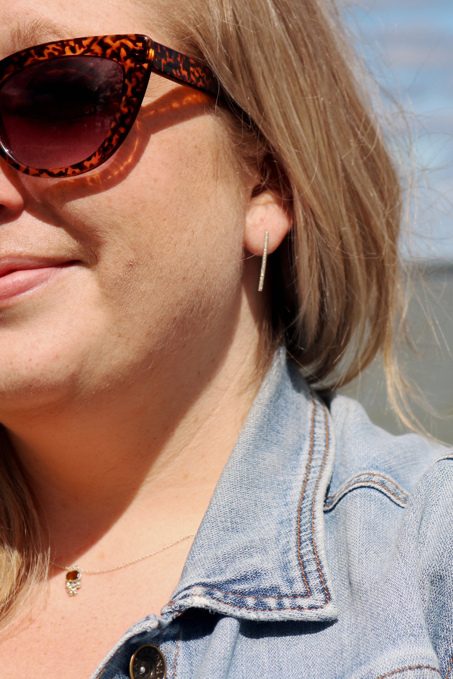 A model wearing sterling silver long bar studs with linear texture.