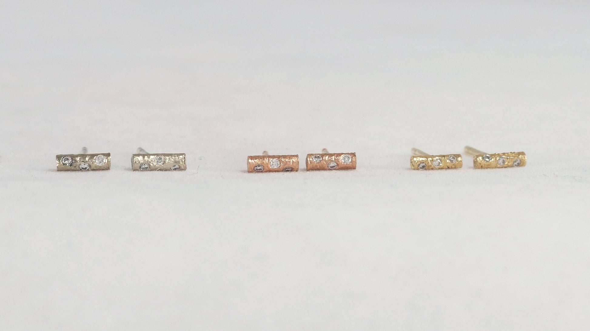 Solid 14k gold bar studs, textured and set with 3 diamonds in each.