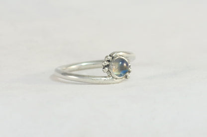 Round natural rainbow moonstone set in sterling silver bezel on a bypass ring band with silver bubble accents. 