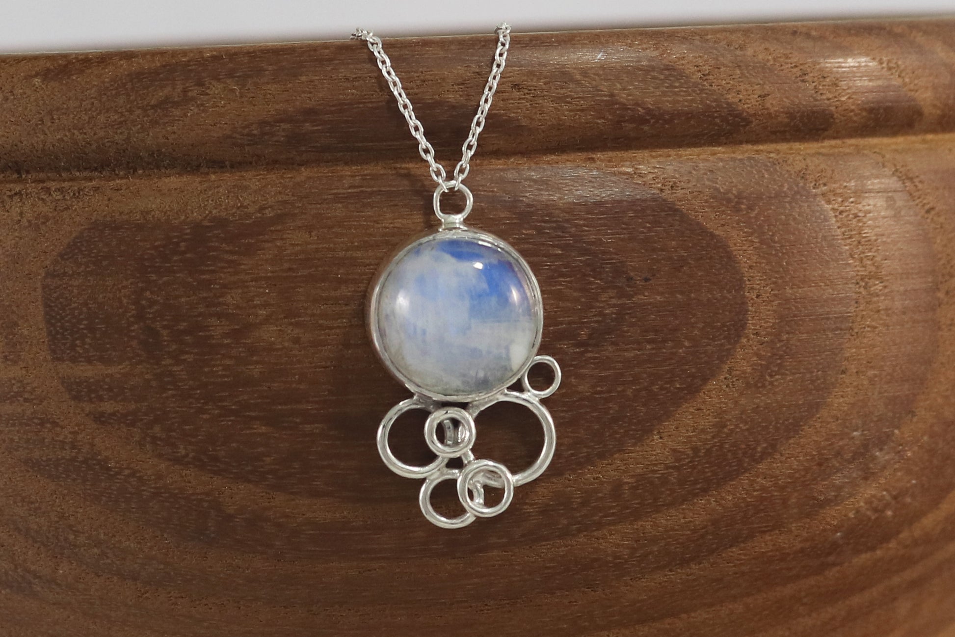 Natural round rainbow moonstone on a silver chain, with 6 silver open circles placed below to look like a cluster of bubbles.