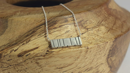 A large sterling silver bar with randomly spaced black lines.