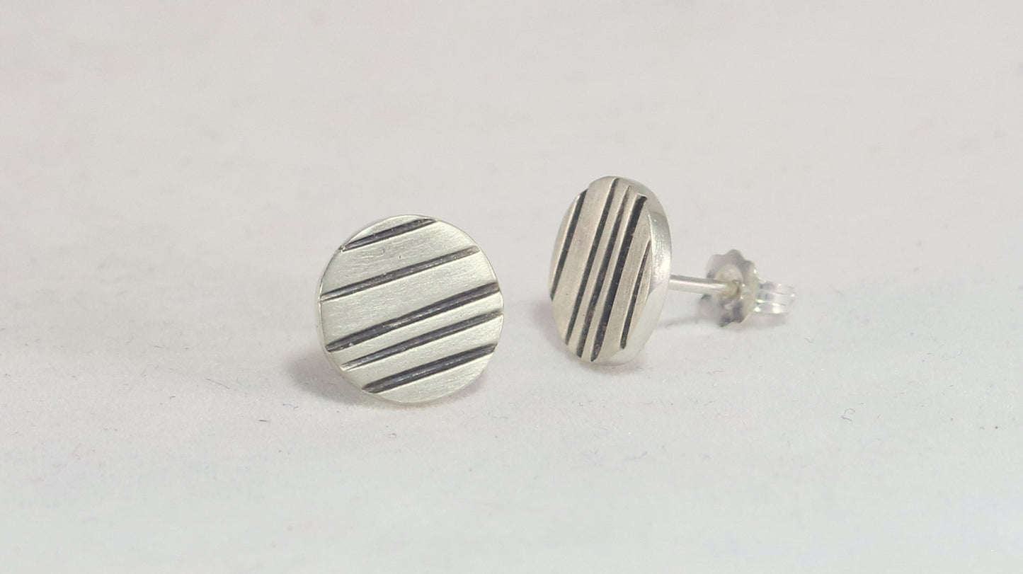 Round silver disc studs with black lines randomly spaced.