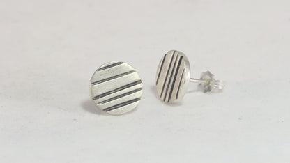 Round silver disc studs with black lines randomly spaced.