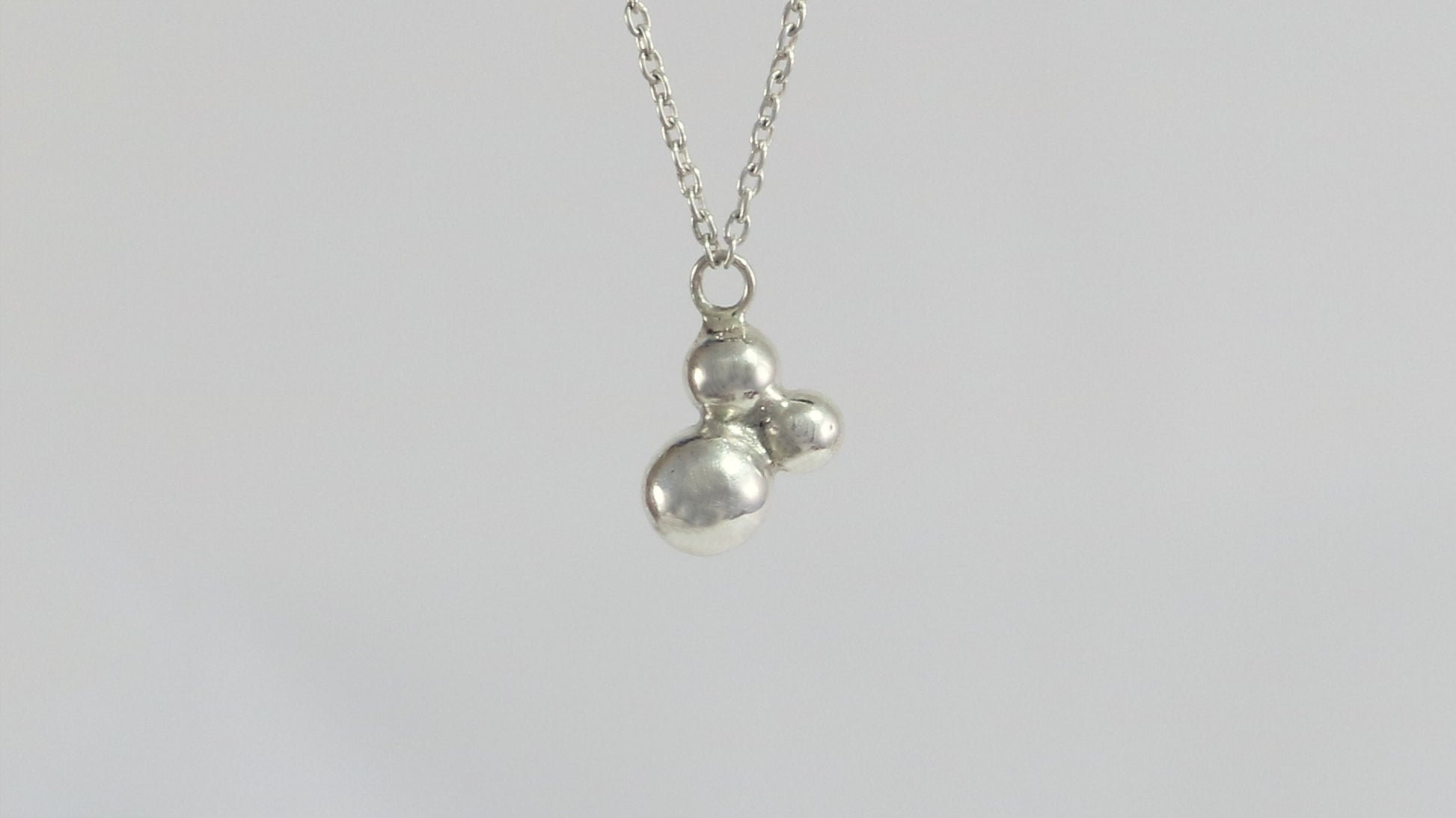 Three sterling silver bubbles in a pyramid on a sterling silver chain.