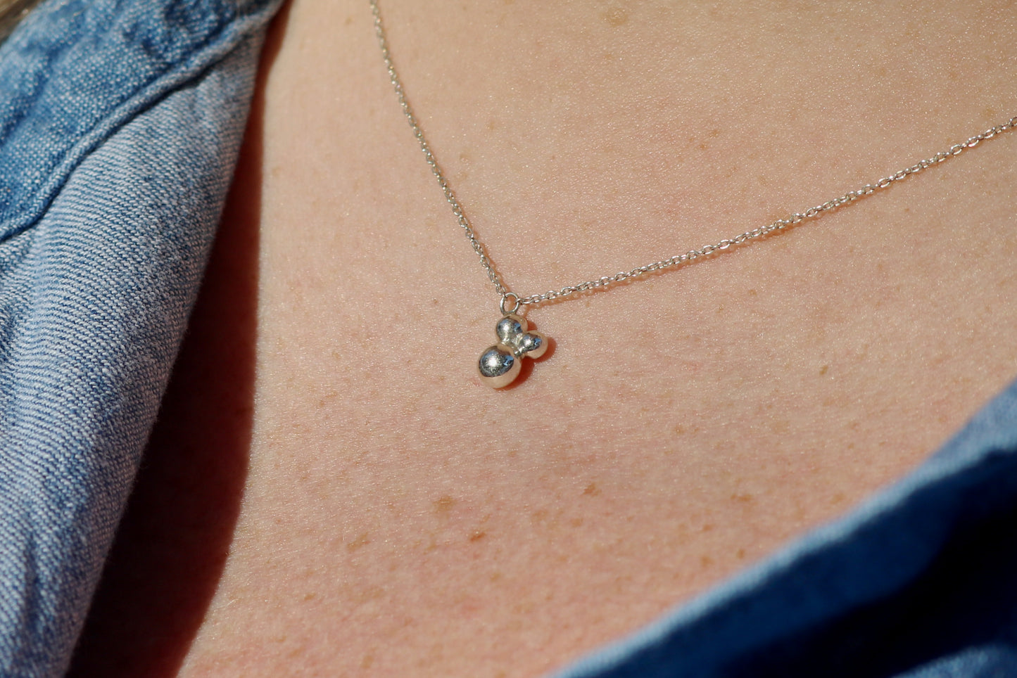 Three sterling silver bubbles in a pyramid on a sterling silver chain.