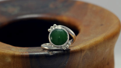 Round natural jade set in sterling silver bezel on a bypass ring band with silver bubble accents. 