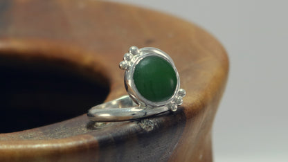 Round natural jade set in sterling silver bezel on a bypass ring band with silver bubble accents. 