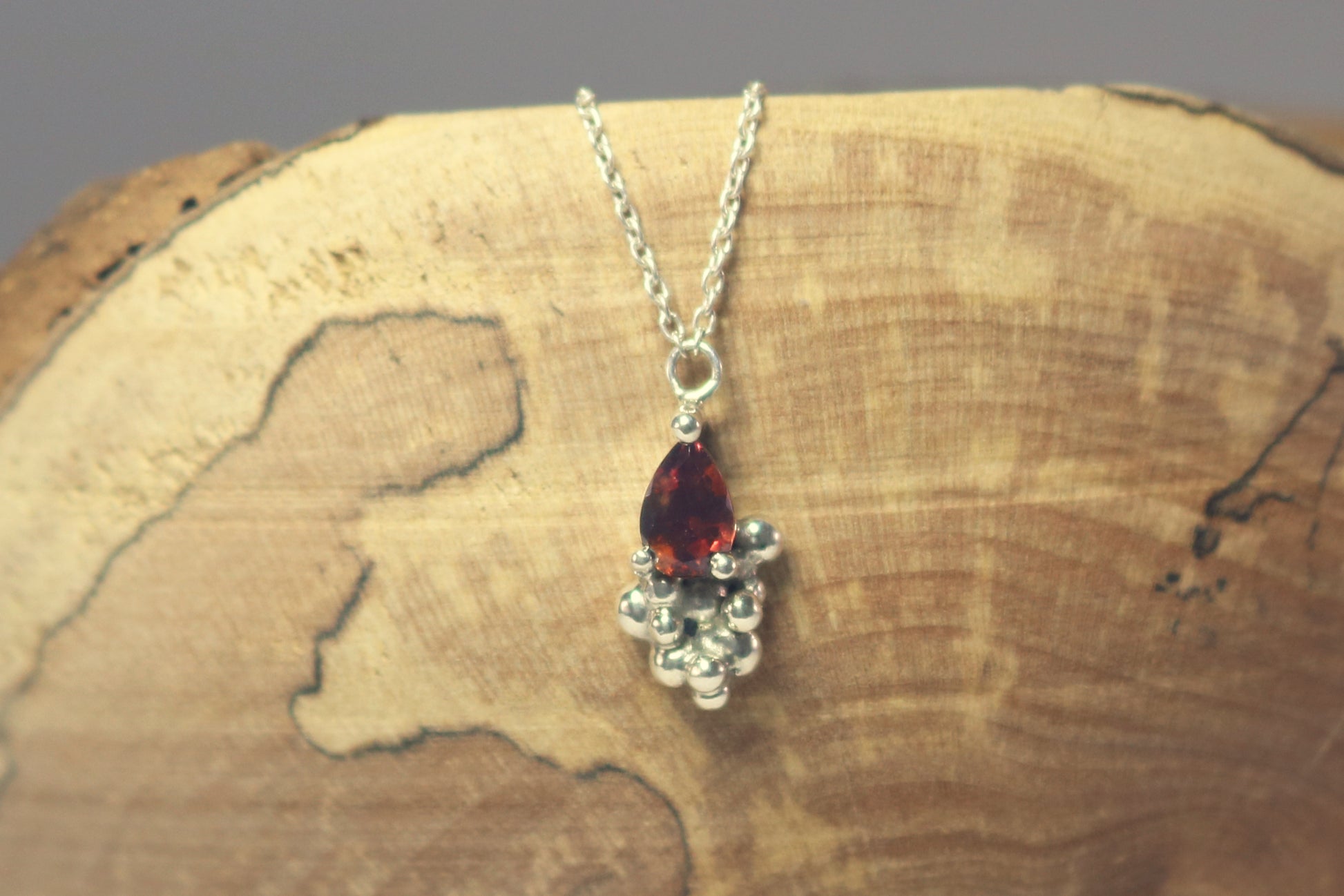 Pear shaped natural gemstone prong set in sterling silver with tumble bubble accent on a sterling silver chain.