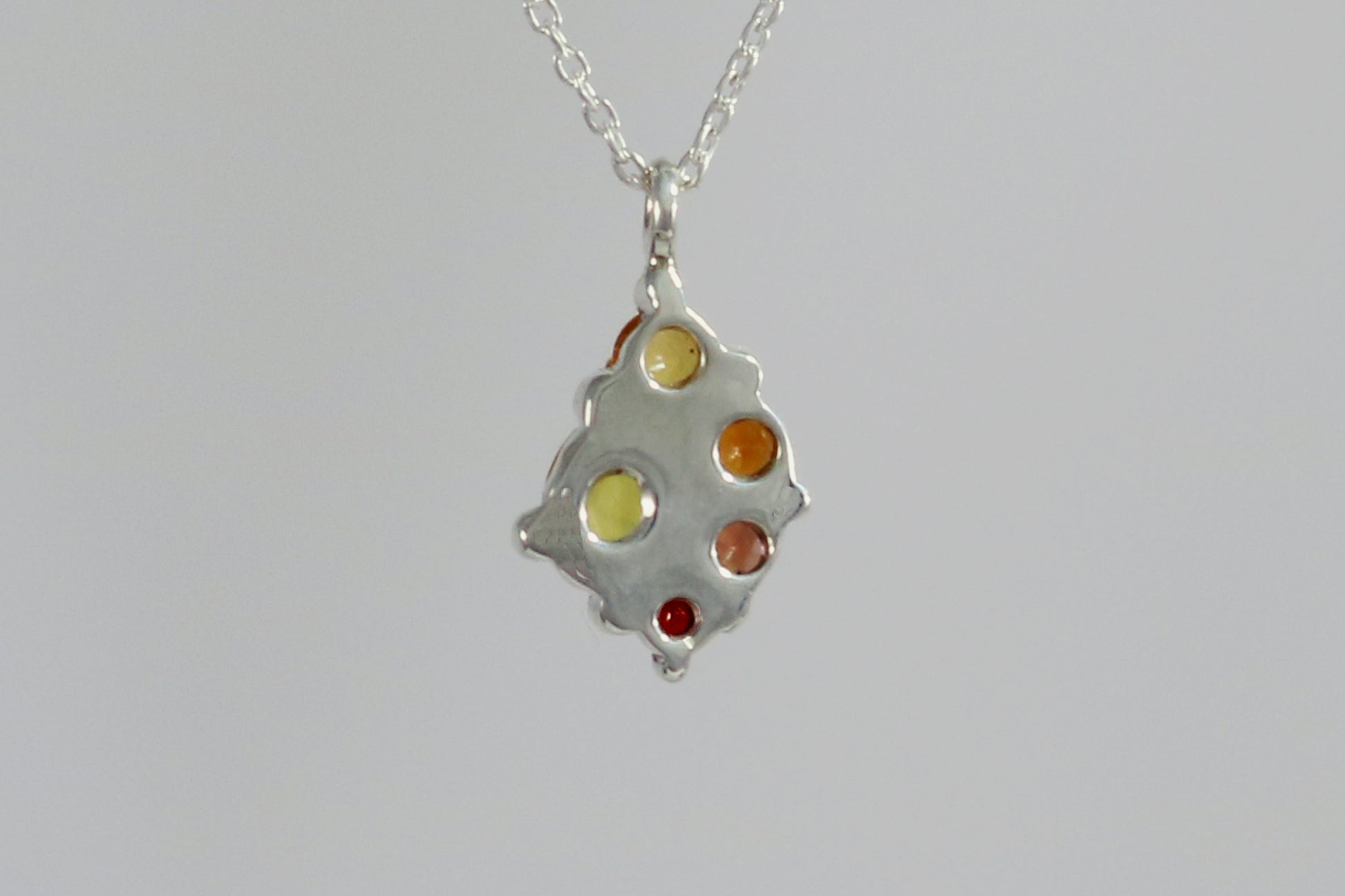 A sterling silver cluster pendant of natural gemstones in a yellow to red gradient on a sterling silver chain.