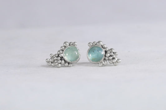 Studs with 8mm round, aquamarines set in sterling silver with silver climbing bubble tumble clusters going up one side of the stone.