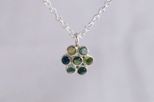 Sterling silver flower shaped pendant set with 7 blue/green tourmaline natural gemstones on a sterling silver chain.