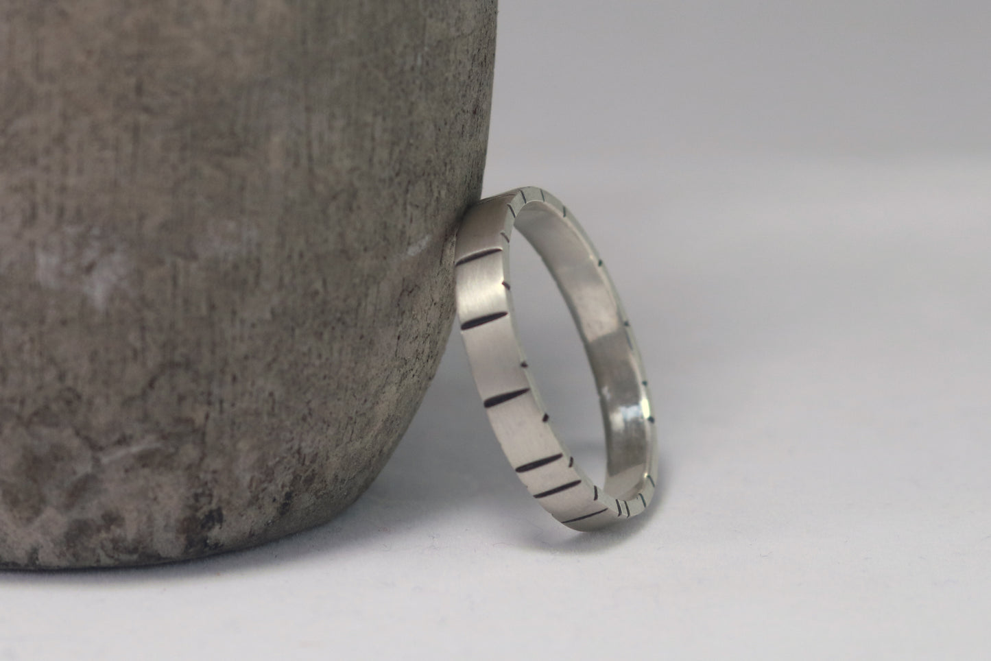 A 4mm silver ring band with randomly spaced black line details.