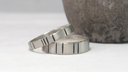 A 4mm and a 6mm silver ring band with randomly spaced black line details.