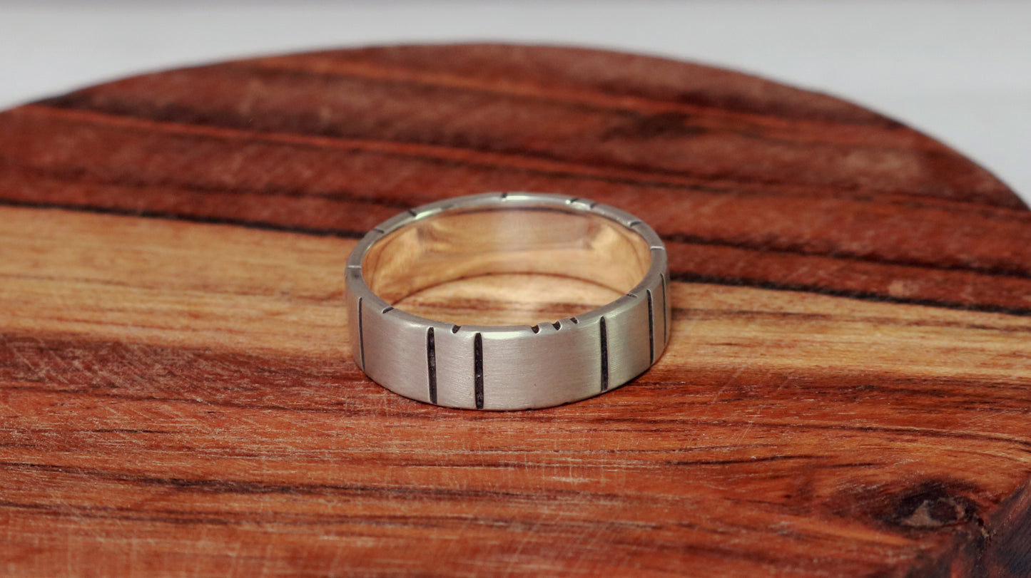 A 6mm thick silver ring band with randomly spaced black line details.